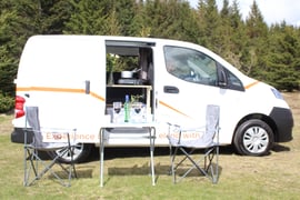 two chairs and a table are included in the nissan nv200 camper van rental